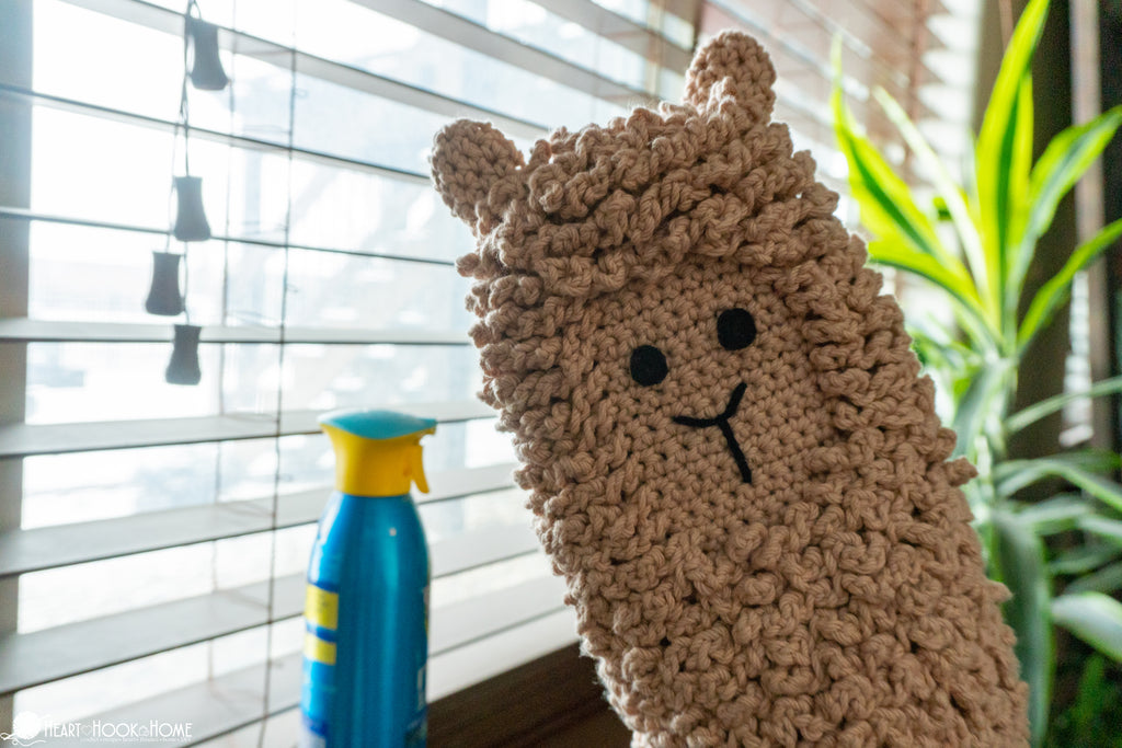crochet llama dusting mitt being used for cleaning